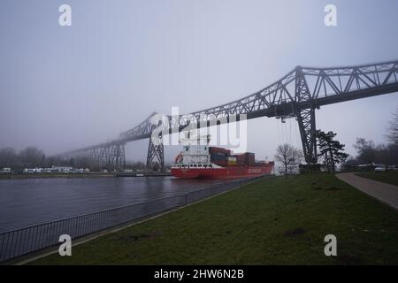 04. März 2022, Schleswig-Holstein, Osterrönfeld: Ein Containerschiff fährt im Morgennebel unter der Rendsburg-Hochbrücke auf dem Nord-Ostsee-Kanal (NOK). Foto: Marcus Brandt/dpa Quelle: dpa picture Alliance/Alamy Live News Stockfoto