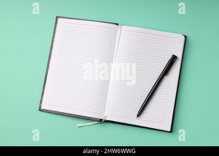 Leeres Notizbuch mit Stift auf mintgrün Hintergrund Stockfoto
