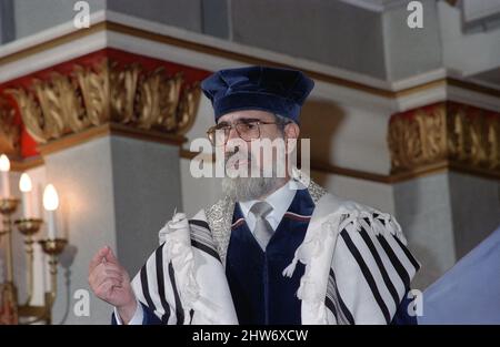 Der Oberrabbiner Lord Jonathan Sacks hält eine Predigt aus der Bima in der Schule (Synagoge). Der Oberrabbiner Jonathan Sacks war Ehrengast für die Aufnahme der letzten Briefe in eine neue Sefer-Torah in der Synagoge der hebräischen Kongregation Singers Hill am Sonntag, dem 15. März 1998. Mitglieder der Gemeinde sowie der Oberrabbiner fügten jeweils einen einzigen Brief hinzu. Stockfoto