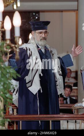 Der Oberrabbiner Lord Jonathan Sacks hält eine Predigt aus der Bima in der Schule (Synagoge). Der Oberrabbiner Jonathan Sacks war Ehrengast für die Aufnahme der letzten Briefe in eine neue Sefer-Torah in der Synagoge der hebräischen Kongregation Singers Hill am Sonntag, dem 15. März 1998. Mitglieder der Gemeinde sowie der Oberrabbiner fügten jeweils einen einzigen Brief hinzu. Stockfoto