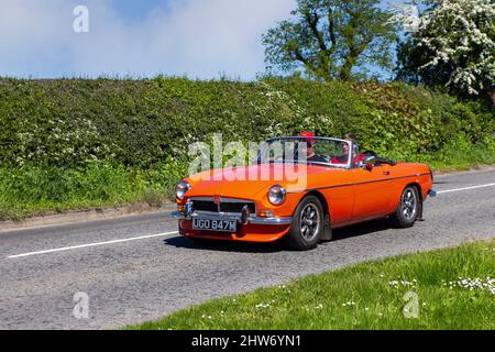 1973 70s siebziger orangefarbener MG B Zweisitzer-britischer Sportwagen auf dem Weg zur Capesthorne Hall Classic May Car Show, Ceshire, Großbritannien Stockfoto