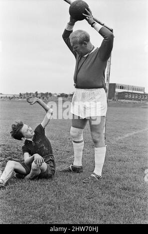 David Bradley (14 Jahre) spielt die Rolle von Billy Casper, abgebildet mit seinem Kestral, auf dem Filmset des Films kes. Hier spielt Billy Casper den Torwart in der Schulfußballspielszene. Mit ihm ist Herr Sugden, gespielt von Brian Glover. Mr. Sugden glaubt, dass er Bobby Charlton ist, der ein Manchester United Shirt trägt und seine Spieler auf dem Spielfeld anordnet. Kes ist ein 1969 veröffentlichter Dramaturgie unter der Regie von Ken Loach und produziert von Tony Garnett. Der Film basiert auf dem Roman A Kestrel for a Knave aus dem Jahr 1968, der vom in Barsley geborenen Autor Barry Hines geschrieben wurde. Der Film belegt den siebten Platz im Briten Stockfoto