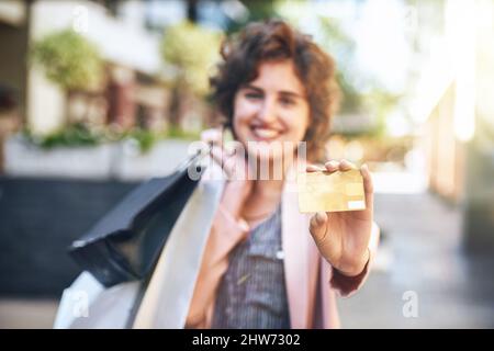 Dadurch sparen Sie Zeit und Ärger. Aufnahme einer Frau, die ihre Kreditkarte beim Einkaufen hochhält. Stockfoto