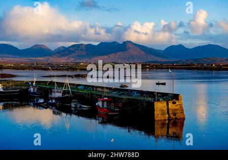 Ein kleines Fischerboot verlässt Roundstone Harbour, Connemara, County Galway, Irland Stockfoto