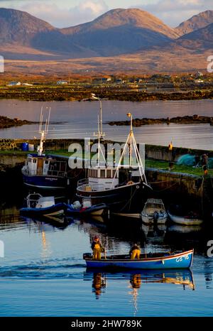 Ein kleines Fischerboot verlässt Roundstone Harbour, Connemara, County Galway, Irland Stockfoto