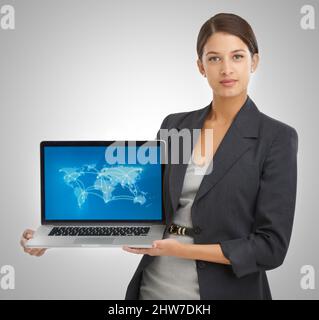 Wir sind global geworden. Studio-Porträt einer Geschäftsfrau mit einem Laptop, auf dem eine Weltkarte mit Standorten zu sehen ist. Stockfoto