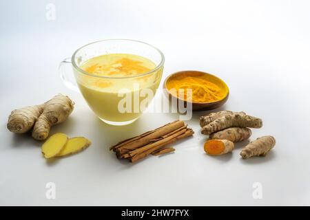 Goldene Kurkuma-Milch mit Ingwer, Zimt und mehr Zutaten, ayurvedisches Getränk, gesund und vegan, hellgrauer Hintergrund mit Kopierraum, ausgewählte en Stockfoto