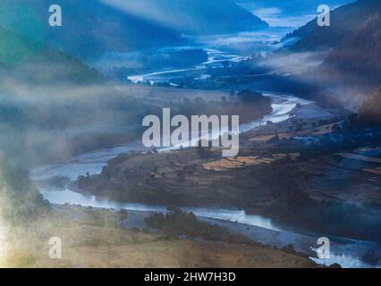 Punakha, Bhutan. Am frühen Morgen Sonne beleuchtet Morgennebel in der Mo River Valley. Stockfoto