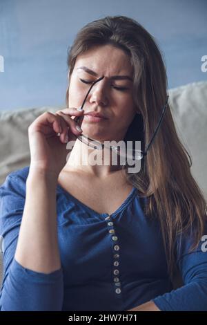 Eine Frau mit Sehproblemen hält eine Brille Stockfoto