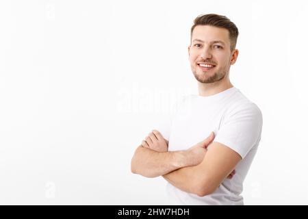 Porträt eines fröhlichen jungen Mannes in einem weißen T-Shirt auf weißem Hintergrund. Der Typ steht und schaut auf die Kamera und lächelt. Stockfoto