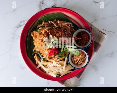 Pad Thai Soft Shell Krabbennudel mit rotem Chili in einem Gericht isoliert auf Matte Draufsicht auf grauem Marmor Hintergrund Stockfoto