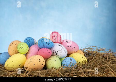 Bunte ostereier auf trockenem Gras auf himmelblauem Hintergrund Stockfoto