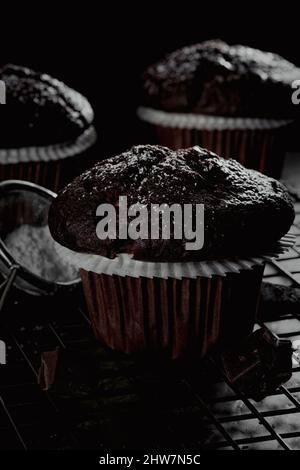 Frisch gebackene Schokoladen-Muffins auf dunklem Hintergrund Stockfoto