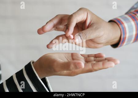 Nahaufnahme der Hand des Mannes, der Pillen hält und sie einer anderen Person gibt Stockfoto