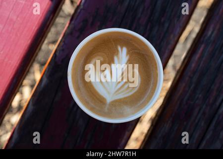 Cappuccino in einer Papiertasse, auf einer Bank im Park, Draufsicht aus der Nähe Stockfoto