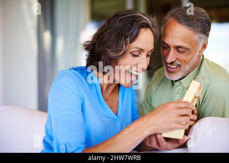Die beste Geburtstagsüberraschung aller Zeiten. Aufnahme einer Frau, die ein Geschenk öffnet. Stockfoto