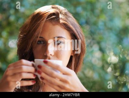 Warmer Sommerkaffee. Porträt einer attraktiven jungen Frau, die sich bei einer Tasse Kaffee im Freien entspannt. Stockfoto