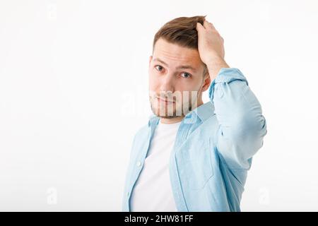 Der junge Mann war aufgebracht, als er seine grauen Haare bemerkte. Haarpflege, Haarausfall grau. Stockfoto