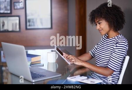 Geschäfte bequem von zu Hause aus erledigen. Eine kurze Aufnahme einer attraktiven jungen Frau, die zu Hause arbeitet. Stockfoto