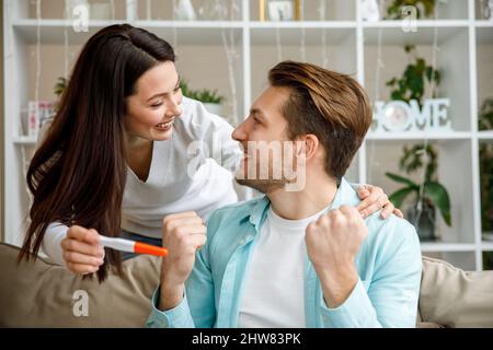 Frau, die ihren Mann mit einem positiven Schwangerschaftstest überraschte, Stockfoto
