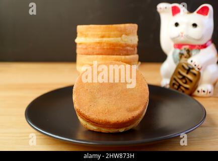 Teller mit Imagawayaki oder Obanyaki, japanische traditionelle Füllung Pan Cakes mit winkenden Cat Maneki-neko Stockfoto