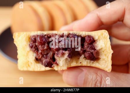 Nahaufnahme köstliches japanisches Azuki Bean Paste gefülltes Dessert namens Imagawayaki oder Obanyaki in der Hand Stockfoto