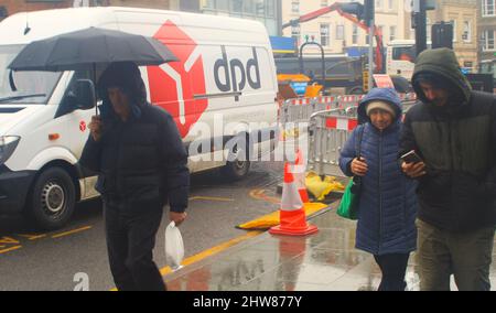 Wetterkonzept - Fußgänger, die im Regen in einer Chelmsford-Straße laufen. Stockfoto