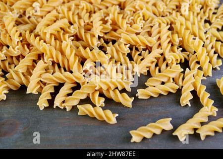 Haufen ungekochte ganze Weizen Fusilli Pasta auf der Rückseite Holzkulisse Stockfoto