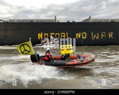 Wedel, Deutschland. 04. März 2022. Aktivisten von Greenpeace haben den Kohlefrachter "Grand T", der auf dem Weg zum Hamburger Hafen mit russischer Kohle beladen ist, mit dem Slogan "No Coal no war" bemalt und mit einem Schlauchboot am Schiff entlang segelt. Quelle: Daniel Bockwoldt/dpa/Alamy Live News Stockfoto