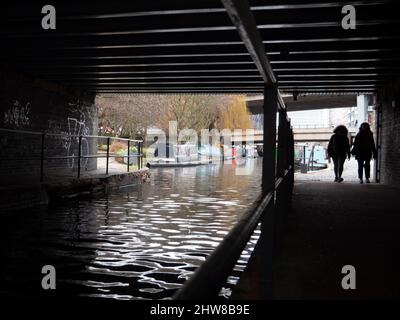 Fußgänger, die auf dem Treidelpfad unter der Brücke Grand Union Canal Paddington laufen Stockfoto