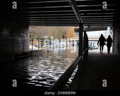 Fußgänger, die auf dem Treidelpfad unter der Brücke Grand Union Canal Paddington laufen Stockfoto