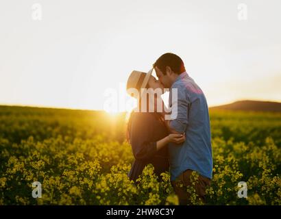 Gemeinsam einen magischen Moment erleben. Aufnahme eines liebevollen jungen Paares, das sich bei Sonnenuntergang einen Kuss teilt. Stockfoto