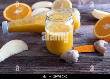 Getränk zur Stärkung des Immunsystems mit einer Orange, Apfel, Ingwer, Kurkuma Schuss Stockfoto