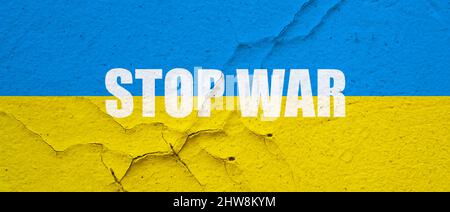 Ukrainische Flagge auf einer Betonwand mit Stop war gemalt Stockfoto