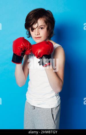 Ich habe einen großen Kampf vor mir. Porträt eines Jungen, der Boxhandschuhe im Studio trägt.