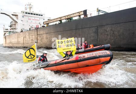 Wedel, Deutschland. 04. März 2022. Auf der Elbe zwischen Wedel (Schleswig-Holstein) und Hamburg segeln Aktivisten von Greenpeace in einem Schlauchboot, um den Kohlefrachter "Grand T", der auf dem Weg zum Hamburger Hafen mit russischer Kohle beladen ist, mit dem Slogan "No Coal no war" zu besetzen. Im Schlauchboot halten Aktivisten ein Banner. Quelle: Daniel Bockwoldt/dpa/Alamy Live News Stockfoto