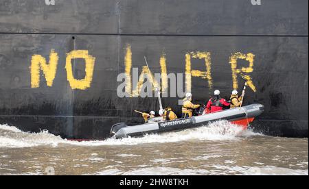 Wedel, Deutschland. 04. März 2022. Aktivisten von Greenpeace fahren auf der Elbe zwischen Wedel (Schleswig-Holstein) und Hamburg in einem Schlauchboot, um den Kohlefrachter "Grand T", der auf dem Weg zum Hamburger Hafen mit russischer Kohle beladen ist, mit dem Slogan "No Coal no war" zu besetzen. Quelle: Daniel Bockwoldt/dpa/Alamy Live News Stockfoto