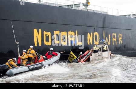 Wedel, Deutschland. 04. März 2022. Aktivisten von Greenpeace fahren auf der Elbe zwischen Wedel (Schleswig-Holstein) und Hamburg mit Schlauchbooten, um den Kohlefrachter "Grand T", der auf dem Weg zum Hamburger Hafen mit russischer Kohle beladen ist, mit dem Slogan "No Coal no war" zu besetzen. Und werden von einem Polizeiboot weggeschoben. Quelle: Daniel Bockwoldt/dpa/Alamy Live News Stockfoto