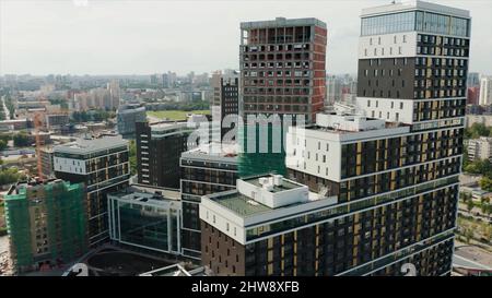 Luftaufnahme eines neu errichteten Luxus-Wohnkomplexes und der Baustelle in Arbeit. Video. Panoramablick auf eine große Stadt auf einem sommerlich sonnigen d Stockfoto