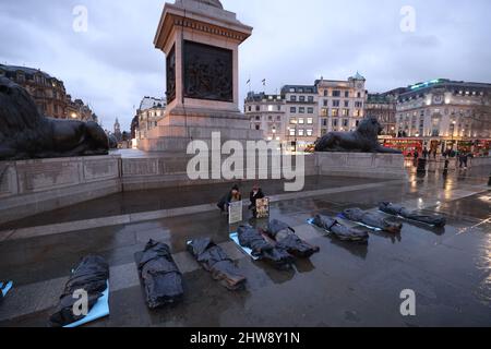 Demonstranten decken sich auf dem Trafalgar Square in London mit Plastikfolien ab, um gegen die russische Invasion von Ukriane zu protestieren. Bilddatum: Freitag, 4. März 2022. Stockfoto