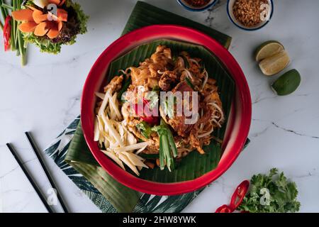 Pad Thai Soft Shell Krabbennudel mit rotem Chili in einem Gericht isoliert auf Matte Draufsicht auf grauem Marmor Hintergrund Stockfoto