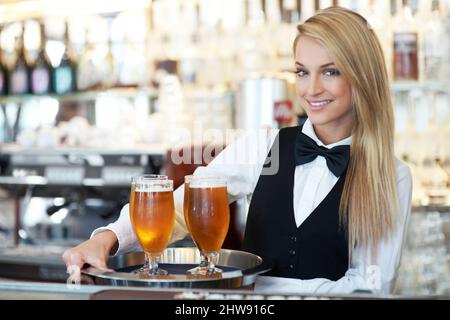 Ein großer Durst nach Leben. Porträt einer schönen Kellnerin, die bestellte Getränke einsammelt und ausliefert. Stockfoto