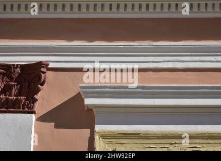 Alte neoklassische Hausfassade mit ockerfarbener Stuckwand, ionischen Säulen und weißem Gips in Nafplio, Griechenland. Stockfoto