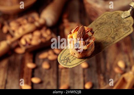 Kleine Kuchen mit Mandeln, Rosinen und Honig auf einem alten Messingspatel. Stockfoto
