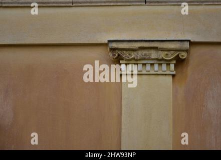 Alte neoklassizistische Hausfassade mit ionischer Ordnungssäule an einer venezianischen ockerfarbenen Stuckwand in Nafplio, Griechenland. Stockfoto