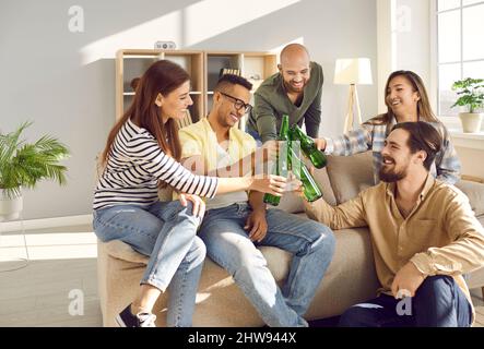 Fröhliche, vielfältige junge Menschen jubeln zu Hause entspannt zu Stockfoto