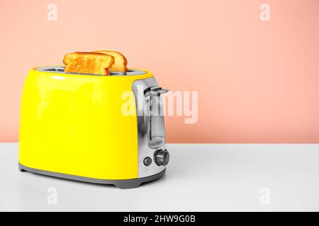 Moderner Toaster mit Brotscheiben auf dem Tisch Stockfoto