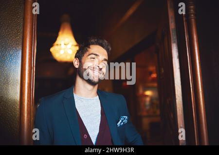 Gekleidet, um zu beeindrucken. Ausgeschnittene Aufnahme eines jungen Mannes, der in einer Bar steht. Stockfoto