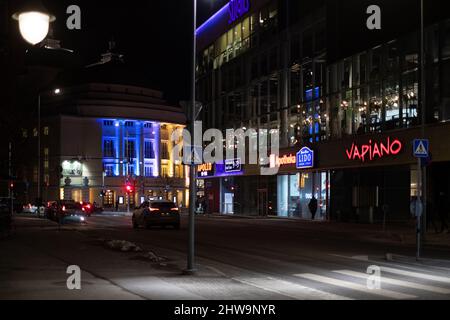 Gebäude der Estnischen Nationaloper bei Nacht in ukrainischen Flaggen-Farben. Seite des Einkaufszentrums Solaris. Unterstützung für die Ukraine. Stockfoto