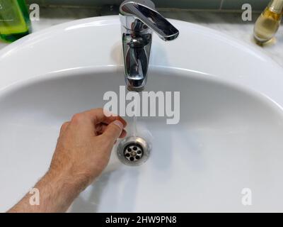 Hand auf ein Waschbecken, das aus dem Wasserhahn lief Stockfoto